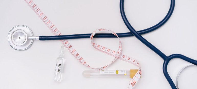a stethoscope, ampoule, and tape measure on a white background