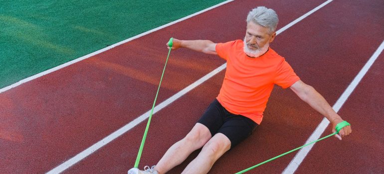 Elderly man exercising on a track with a resistance band